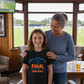 Woman and young boy standing together in a room with a view of a sports field.  The young boy is wearing a Cows Corner T-shirt with the funny and sweet cricket slogan on the front that reads 'Mum’s Decision is Final – No DRS Available'. Cows Corner gifts are perfect for sport-mad fans, these gifts work brilliantly for birthdays, new baby celebrations, Father’s Day, Mother’s Day, Christmas, anniversaries, thank you gifts, end-of-season team awards, graduations, retirements, and just-because moments.