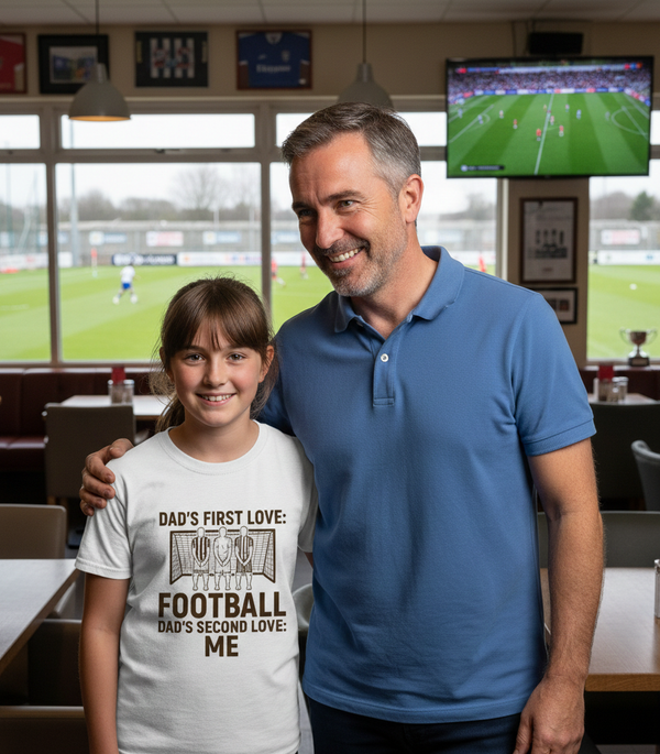 Man and young girl standing together in a sports bar with a TV showing a football game.  The girl is wearing a Cows Corner T-shirt with the funny and sweet football slogan on the front that reads 'Dad’s First Love: Football. Dad’s Second Love: Me'.  Cows Corner gifts are perfect for sport-mad fans, these gifts work brilliantly for birthdays, new baby celebrations, Father’s Day, Mother’s Day, Christmas, anniversaries, thank you gifts, end-of-season team awards, graduations, retirements, and just-because