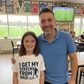 Man and young girl standing together in a sports facility with a soccer field in the background.  The girl is wearing a Cows Corner T-shirt with the funny and sweet football slogan on the front that reads 'I Get My Tekkers From Dad'.  Cows Corner gifts are perfect for sport-mad fans, these gifts work brilliantly for birthdays, new baby celebrations, Father’s Day, Mother’s Day, Christmas, anniversaries, thank you gifts, end-of-season team awards, graduations, retirements, and just-because moments