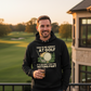 Man wearing a black hoodie with a humorous golf-themed graphic, standing on a golf course. The man is wearing a Cows Corner hoodie with a funny golf slogan 'You’d Be Great at Golf if It Wasn’t for the Hitting Part'. Cows Corner gifts are perfect for sport-mad fans, these gifts work brilliantly for birthdays, new baby celebrations, Father’s Day, Mother’s Day, Christmas, anniversaries, thank you gifts, end-of-season team awards, graduations, retirements, and just-because moments when you want to raise a smile