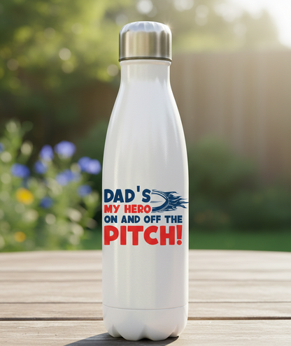 White water bottle with a motivational quote on a wooden surface with a blurred natural background. This is a Cows Corner water bottle with a funny rugby slogan 'Dad’s My Hero on and off the Pitch!'. Cows Corner gifts are perfect for sport-mad fans, these gifts work brilliantly for birthdays, new baby celebrations, Father’s Day, Mother’s Day, Christmas, anniversaries, thank you gifts, end-of-season team awards, graduations, retirements, and just-because moments when you want to raise a smile. 
