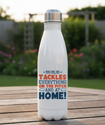 White water bottle with colorful text on a wooden surface with a garden background. This is a Cows Corner water bottle with a funny rugby slogan 'My Mum Tackles Everything on the Pitch and at Home!'. Cows Corner gifts are perfect for sport-mad fans, these gifts work brilliantly for birthdays, new baby celebrations, Father’s Day, Mother’s Day, Christmas, anniversaries, thank you gifts, end-of-season team awards, graduations, retirements, and just-because moments when you want to raise a smile. 
