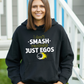 A lady wearing a black hoodie with a funny tennis slogan on the front that reads 'I Don't Smash Rackets Just Egos'