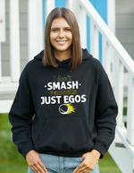 A lady wearing a black hoodie with a funny tennis slogan on the front that reads 'I Don't Smash Rackets Just Egos'