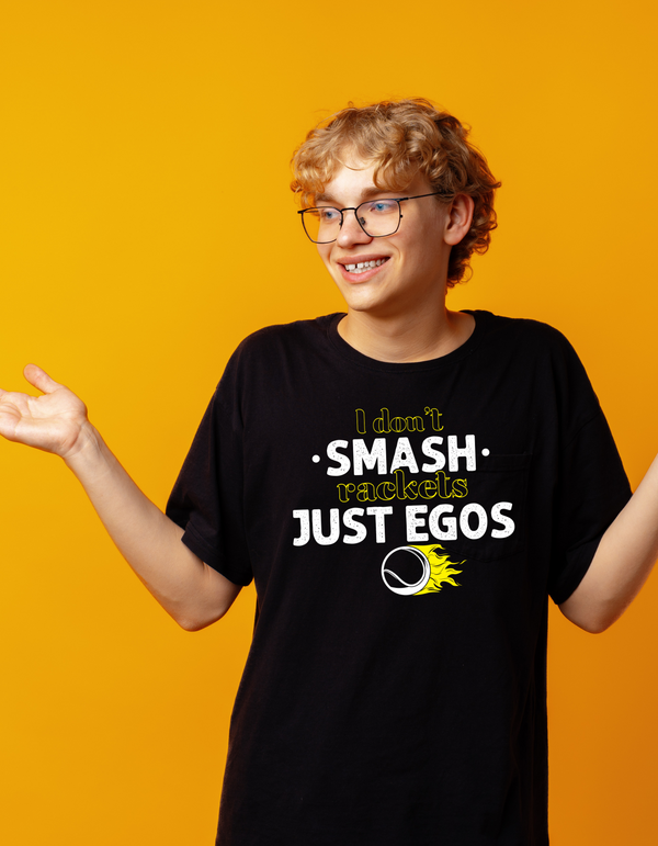 A man wearing a black t-shirt that has a funny tennis slogan on the front that reads 'I Don't Smash Rackets Just Egos'