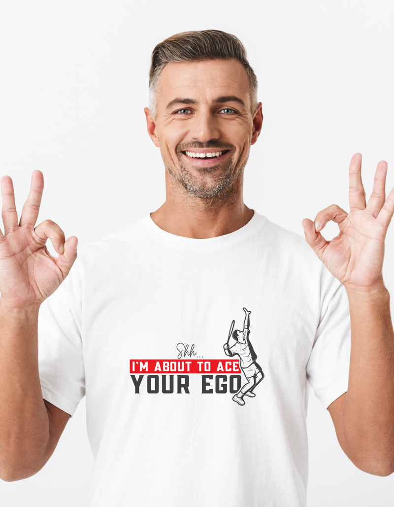 A man wearing a white t-shirt with a funny tennis slogan on the front that reads 'Shh....i'm About To Ace Your Ego'