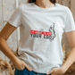 A lady wearing a white t-shirt with a funny tennis slogan on the front that reads 'Shh....i'm About To Ace Your Ego'