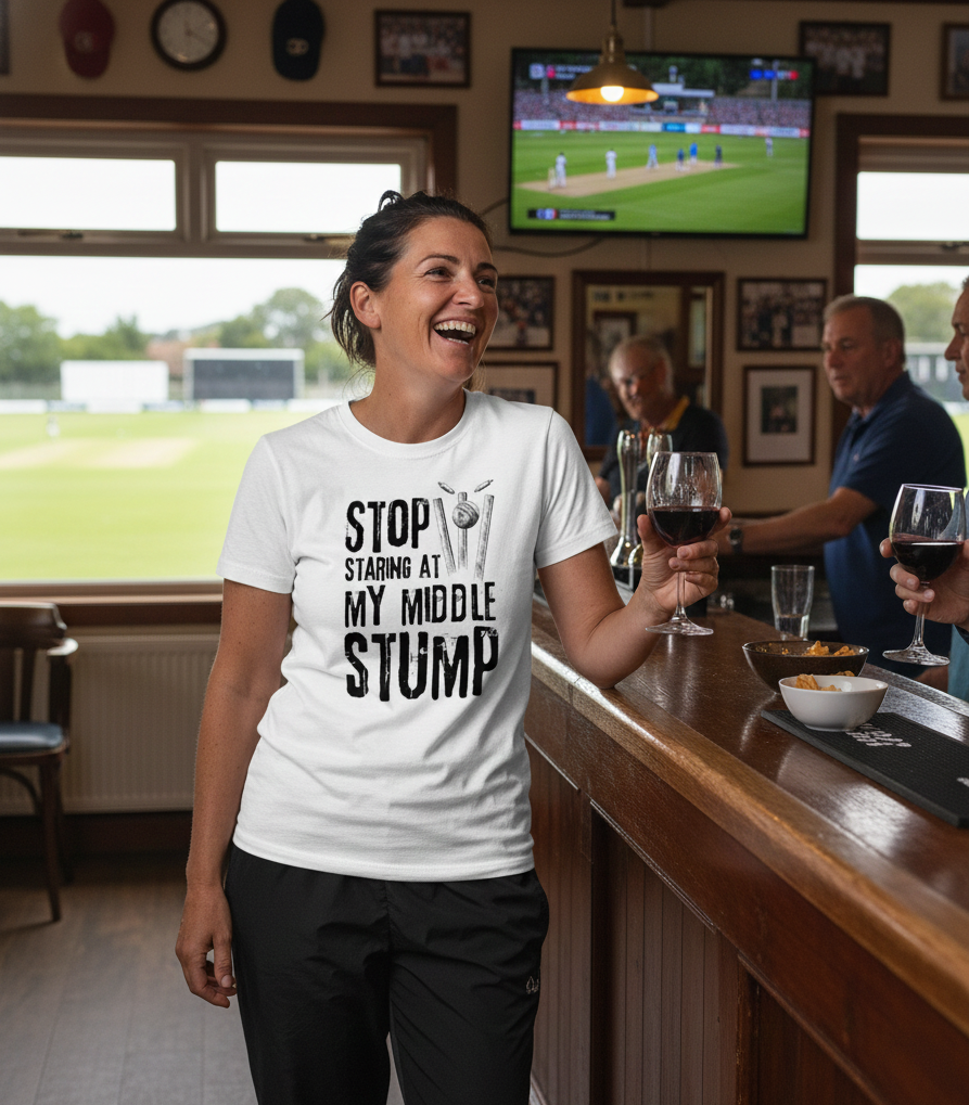 Woman in a bar wearing a t-shirt with a cricket-themed message, holding a glass of wine.  The lady is wearing a Cows Corner t-shirt with the funny cricket saying on the front that reads 'Stop Staring At My Middle Stump'