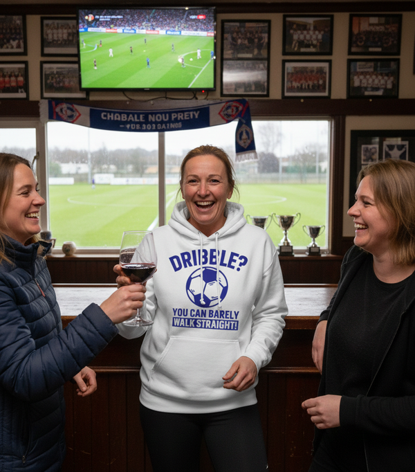 Three women in a pub with a television showing a sports event, one wearing a hoodie with a humorous soccer-themed message. The lady is wearing a Cows Corner hoodie with the funny football slogan 'Dribble You Can Barely Walk Straight!'. Cows Corner gifts are perfect for sport-mad fans, these gifts work brilliantly for birthdays, new baby celebrations, Father’s Day, Mother’s Day, Christmas, anniversaries, thank you gifts, end-of-season team awards, graduations, retirements, and just-because moments 