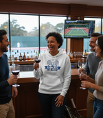Group of people enjoying wine and conversation in a bar with a sports TV in the background. The lady is wearing a Cows Corner hoodie with the funny tennis slogan 'Game, Set, Mismatch'. Cows Corner gifts are perfect for sport-mad fans, these gifts work brilliantly for birthdays, new baby celebrations, Father’s Day, Mother’s Day, Christmas, anniversaries, thank you gifts, end-of-season team awards, graduations, retirements, and just-because moments when you want to raise a smile. 

