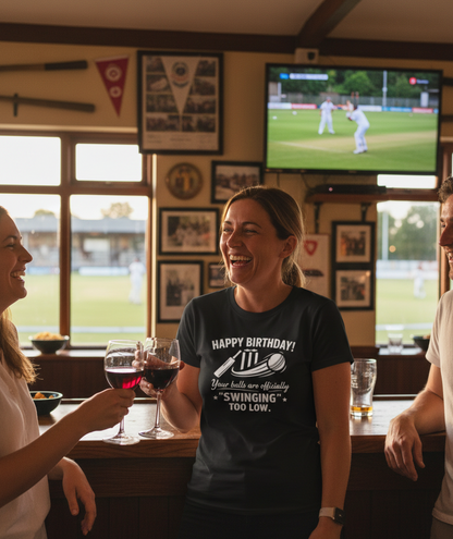 People in a pub watching a sports match on television with a woman in a birthday t-shirt. The lady is wearing a Cows Corner t-shirt with the funny cricket birthday slogan that reads 'Happy Birthday! Your balls are officially 'swinging' too low.' Cows Corner gifts are perfect for sport-mad fans, these gifts work brilliantly for birthdays, new baby celebrations, Father’s Day, Mother’s Day, Christmas, anniversaries, thank you gifts, end-of-season team awards, graduations, retirements, and just-because moments 