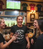 People in a bar watching sports on TV with a woman in a humorous t-shirt.  The lady is wearing a Cows Corner T-shirt with the funny fantasy football slogan on the front that reads 'Talk Big, Play Sh*t, Finish Last'. Cows Corner gifts are perfect for sport-mad fans, these gifts work brilliantly for birthdays, new baby celebrations, Father’s Day, Mother’s Day, Christmas, anniversaries, thank you gifts, end-of-season team awards, graduations, retirements, and just-because moments when you want to raise a smile