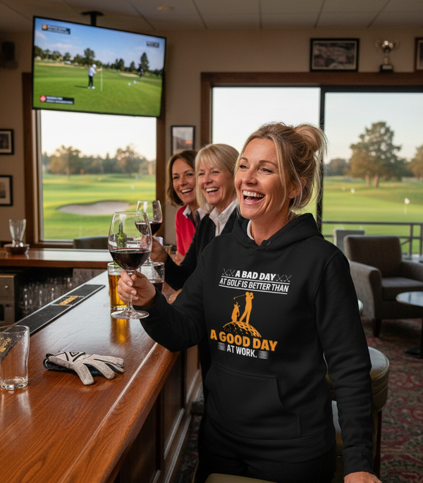 People enjoying drinks and watching golf on TV in a bar with a golf course view. The lady is wearing a Cows Corner hoodie with a funny golf slogan 'A Bad Day at Golf Is Better Than a Good Day at Work'.  Cows Corner gifts are perfect for sport-mad fans, these gifts work brilliantly for birthdays, new baby celebrations, Father’s Day, Mother’s Day, Christmas, anniversaries, thank you gifts, end-of-season team awards, graduations, retirements, and just-because moments when you want to raise a smile. 
