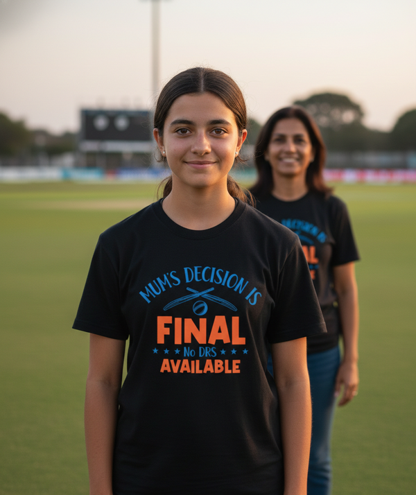 Two people wearing black t-shirts with humorous text on a sports field. The girl is wearing a Cows Corner t-shirt with the funny cricket slogan 'Mum’s Decision is Final – No DRS Available'. Cows Corner gifts are perfect for sport-mad fans, these gifts work brilliantly for birthdays, new baby celebrations, Father’s Day, Mother’s Day, Christmas, anniversaries, thank you gifts, end-of-season team awards, graduations, retirements, and just-because moments when you want to raise a smile. 
