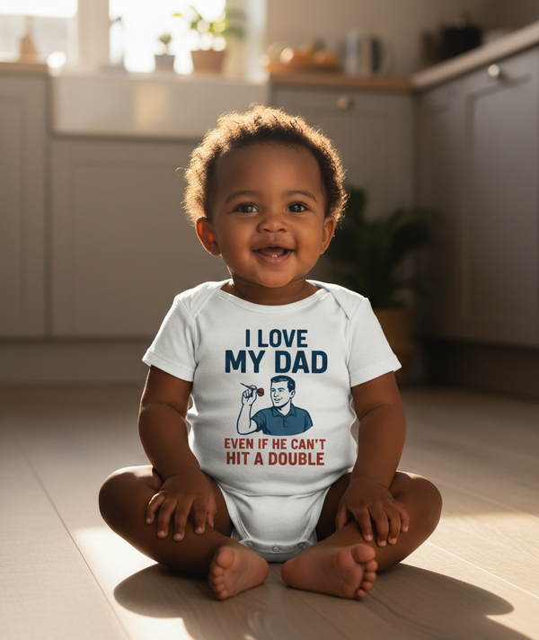 Child wearing a Cows Corner baby grow with the funny darts slogan 'I Love My Dad… Even If He Can’t Hit A Double'. Cows Corner gifts are perfect for sport-mad fans, these gifts work brilliantly for birthdays, new baby celebrations, Father’s Day, Mother’s Day, Christmas, anniversaries, thank you gifts, end-of-season team awards, graduations, retirements, and just-because moments when you want to raise a smile. 
