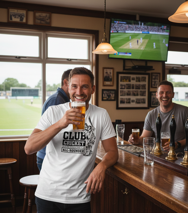 Man in a bar holding a beer, wearing a Cows Corner T-shirt with a funny cricket slogan on the front that reads 'Club Cricket where Everyone’s an All-Rounder'.  Cows Corner gifts are perfect for sport-mad fans, these gifts work brilliantly for birthdays, new baby celebrations, Father’s Day, Mother’s Day, Christmas, anniversaries, thank you gifts, end-of-season team awards, graduations, retirements, and just-because moments when you want to raise a smile. 