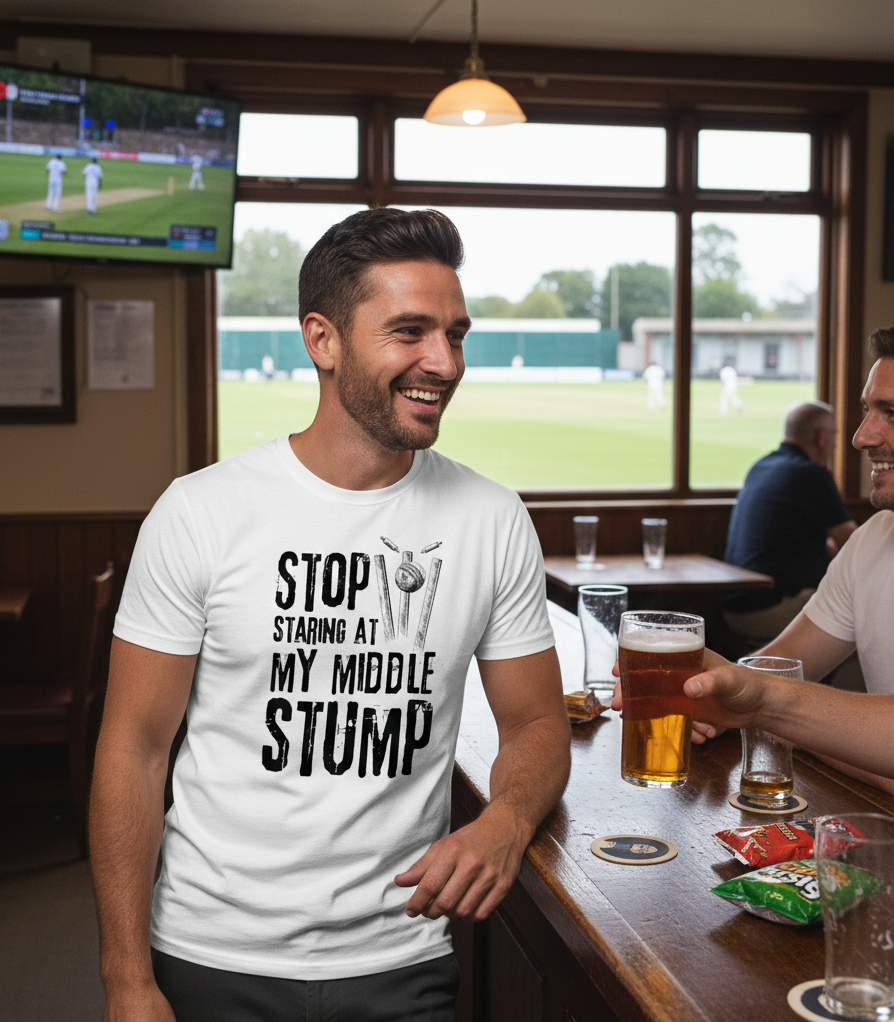 Man wearing a t-shirt with a humorous cricket-related message in a pub setting.  The man is wearing a Cows Corner t-shirt with the funny cricket saying on the front that reads 'Stop Staring At My Middle Stump'