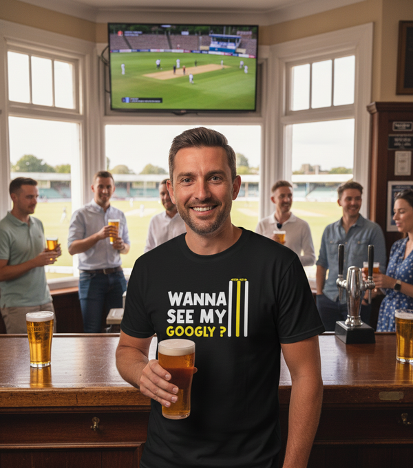 Man in a pub wearing a t-shirt with a humorous question, holding a beer.  The man is wearing a Cows Corner t-shirt with the funny cricket slogan on the front that says 'Wanna See My Googly?  Funny Cricket T-Shirt'