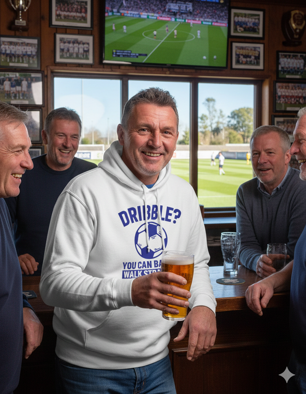 Man in a pub wearing a hoodie with a sports-themed design, holding a beer. The man is wearing a Cows Corner hoodie with the funny football slogan 'Dribble You Can Barely Walk Straight!'. Cows Corner gifts are perfect for sport-mad fans, these gifts work brilliantly for birthdays, new baby celebrations, Father’s Day, Mother’s Day, Christmas, anniversaries, thank you gifts, end-of-season team awards, graduations, retirements, and just-because moments when you want to raise a smile. 
