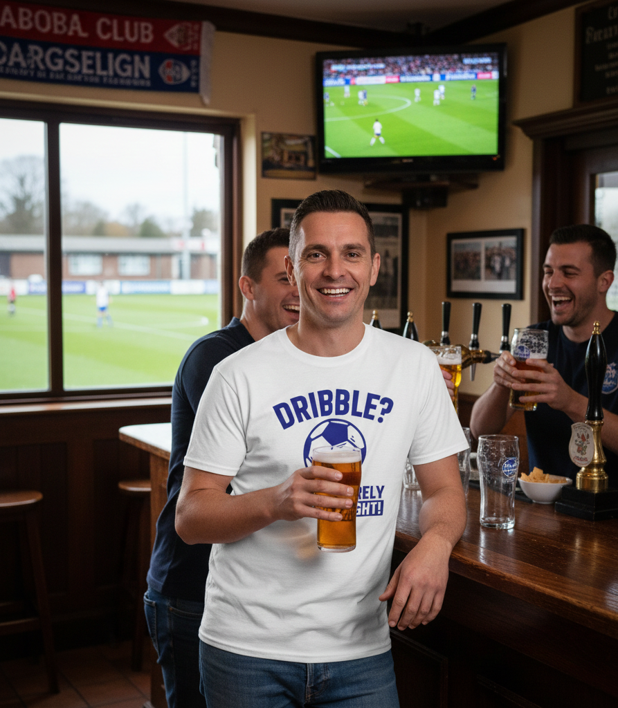 Man in a pub wearing a Cows Corner T-shirt with the funny football slogan on th  front that reads 'Dribble You Can Barely Walk Straight!'   Cows Corner gifts are perfect for sport-mad fans, these gifts work brilliantly for birthdays, new baby celebrations, Father’s Day, Mother’s Day, Christmas, anniversaries, thank you gifts, end-of-season team awards, graduations, retirements, and just-because moments when you want to raise a smile. Designed for people who appreciate thoughtful gifting with a playful edge,