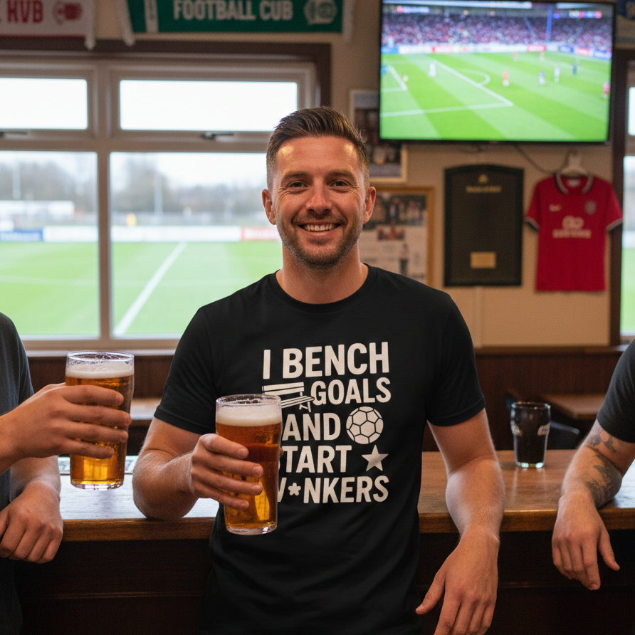 Man holding a beer in a pub with a TV showing a football match in the background.  Man wearing a Cows Corner t-shirt with funny fantasy football slogan I Bench Goals and Start W*ankers.   Cows Corner gifts are perfect for sport-mad fans, these gifts work brilliantly for birthdays, new baby celebrations, Father’s Day, Mother’s Day, Christmas, anniversaries, thank you gifts, end-of-season team awards, graduations, retirements, and just-because moments when you want to raise a smile. 
