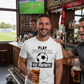 Man in a bar wearing a Cows Corner T-shirt with the funny football slogan on the front that reads'Play Football Not Fortnite!' t-shirt, holding a beer.  Cows Corner gifts are perfect for sport-mad fans, these gifts work brilliantly for birthdays, new baby celebrations, Father’s Day, Mother’s Day, Christmas, anniversaries, thank you gifts, end-of-season team awards, graduations, retirements, and just-because moments when you want to raise a smile. Designed for people who appreciate thoughtful gift