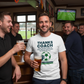A group of men in a pub with one wearing a 'Thanks Coach' t-shirt, holding a beer. The man is wearing a Cows Corner t-shirt with the football slogan on the front that reads 'Thanks Coach From the First Touch to Final Whistle, You’ve Been the Heat of It All'. Cows Corner gifts are perfect for sport-mad fans, these gifts work brilliantly for birthdays, new baby celebrations, Father’s Day, Mother’s Day, Christmas, anniversaries, thank you gifts, end-of-season team awards, graduations, retirements