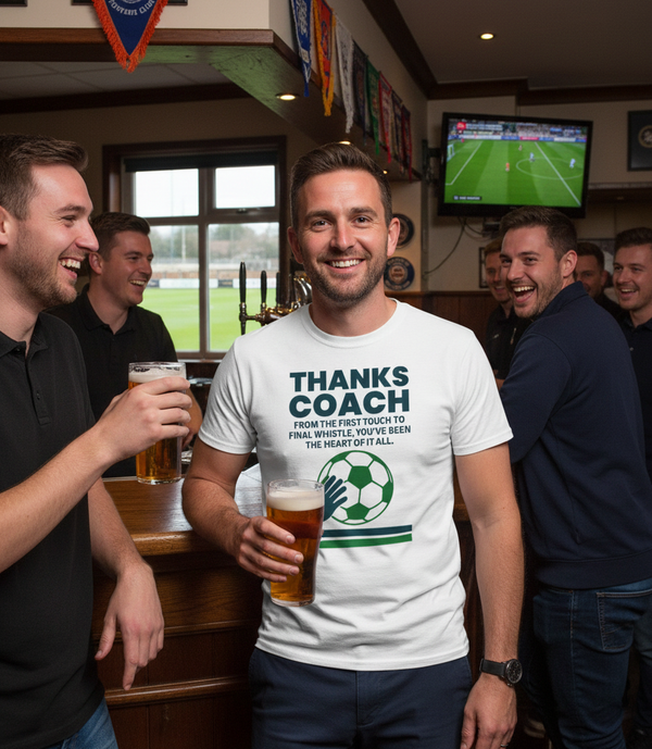 A group of men in a pub with one wearing a 'Thanks Coach' t-shirt, holding a beer. The man is wearing a Cows Corner t-shirt with the football slogan on the front that reads 'Thanks Coach From the First Touch to Final Whistle, You’ve Been the Heat of It All'. Cows Corner gifts are perfect for sport-mad fans, these gifts work brilliantly for birthdays, new baby celebrations, Father’s Day, Mother’s Day, Christmas, anniversaries, thank you gifts, end-of-season team awards, graduations, retirements
