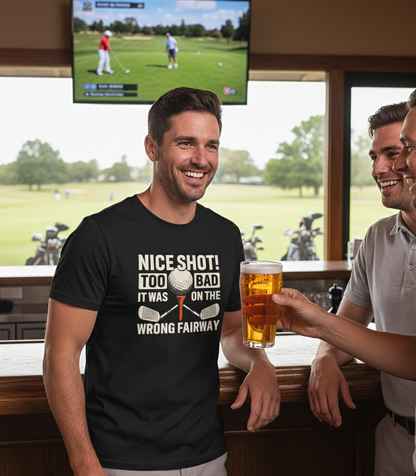 Man wearing a black t-shirt with a humorous golf-themed design, holding a beer, in a bar setting with a TV showing a golf game. The man is wearing a Cows Corner t-shirt with the funny golf slogan on the front that reads 'Nice Shot! Too Bad It Was on the Wrong Fairway'. Cows Corner gifts are perfect for sport-mad fans, these gifts work brilliantly for birthdays, new baby celebrations, Father’s Day, Mother’s Day, Christmas, anniversaries, thank you gifts, end-of-season team awards, graduations, retirements