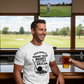 Man in a bar wearing a white t-shirt with a golf-themed design, holding a beer. The man is wearing a Cows Corner t-shirt with a funny golf slogan on the front that reads 'Your Swing Is Proof That Money Can’t Buy Skill'.  Cows Corner gifts are perfect for sport-mad fans, these gifts work brilliantly for birthdays, new baby celebrations, Father’s Day, Mother’s Day, Christmas, anniversaries, thank you gifts, end-of-season team awards, graduations, retirements, and just-because moments 