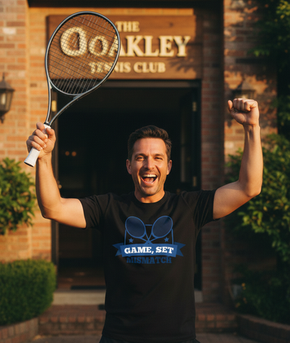 Man holding a tennis racket in front of 'The Oakley Tennis Club' building. The man is wearing a Cows Corner t-shirt with the funny tennis slogan 'Game, Set, Mismatch'. Cows Corner gifts are perfect for sport-mad fans, these gifts work brilliantly for birthdays, new baby celebrations, Father’s Day, Mother’s Day, Christmas, anniversaries, thank you gifts, end-of-season team awards, graduations, retirements, and just-because moments when you want to raise a smile. 
