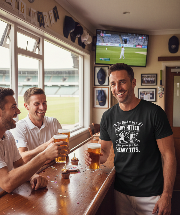Three men in a pub watching a sports game on TV, one wearing a humorous t-shirt. A man wearing a Cows Corner t-shirt with the funny cricket birthday slogan 'You Used to be a Heavy Hitter. Now you’ve Just Got Heavy Tits.' Cows Corner gifts are perfect for sport-mad fans, these gifts work brilliantly for birthdays, new baby celebrations, Father’s Day, Mother’s Day, Christmas, anniversaries, thank you gifts, end-of-season team awards, graduations, retirements, and just-because moments 
