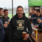 Man wearing a Cows Corner funny fantasy football hoodie with 'Fantasy Football is Ruining My Life' text, holding a beer, surrounded by others in a bar setting. Cows Corner gifts are perfect for sport-mad fans, these gifts work brilliantly for birthdays, new baby celebrations, Father’s Day, Mother’s Day, Christmas, anniversaries, thank you gifts, end-of-season team awards, graduations, retirements, and just-because moments when you want to raise a smile. Designed for people who appreciate thoughtful gifting 