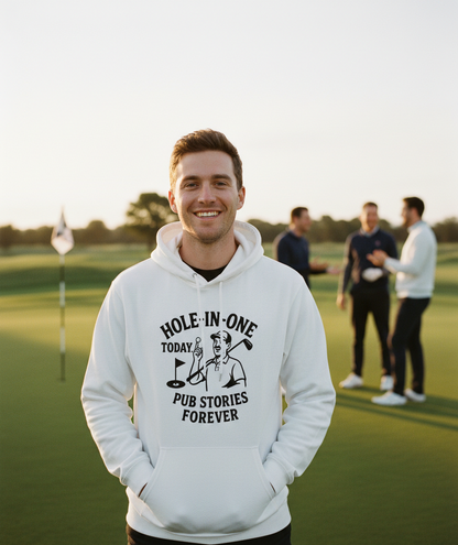 Man wearing a white hoodie with a humorous golf-themed design on a golf course. The man is wearing a Cows Corner hoodie with the funny golf slogan 'Hole-In-One Today… Pub Stories Forever'. Cows Corner gifts are perfect for sport-mad fans, these gifts work brilliantly for birthdays, new baby celebrations, Father’s Day, Mother’s Day, Christmas, anniversaries, thank you gifts, end-of-season team awards, graduations, retirements, and just-because moments when you want to raise a smile. 
