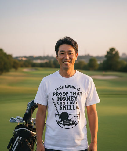 Man on a golf course wearing a white t-shirt with a humorous golf-themed message. The man is wearing a Cows Corner t-shirt with the funny golf slogan 'Your Swing Is Proof That Money Can’t Buy Skill'. Cows Corner gifts are perfect for sport-mad fans, these gifts work brilliantly for birthdays, new baby celebrations, Father’s Day, Mother’s Day, Christmas, anniversaries, thank you gifts, end-of-season team awards, graduations, retirements, and just-because moments when you want to raise a smile. 
