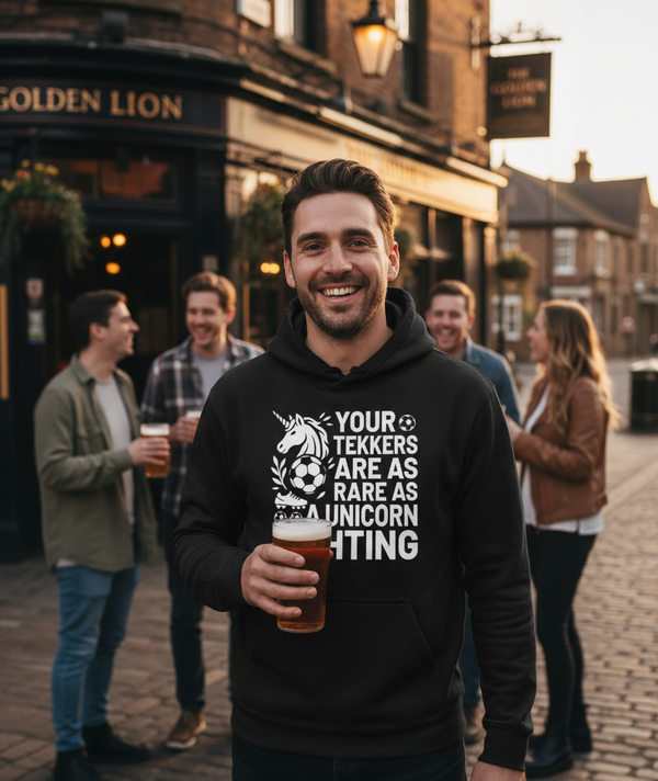 Man wearing a hoodie with a humorous design, standing in a pub courtyard with others. The man is wearing a Cows Corner hoodie with a funny football slogan 'Your Tekkers Are As Rare as a Unicorn Sighting'. Cows Corner gifts are perfect for sport-mad fans, these gifts work brilliantly for birthdays, new baby celebrations, Father’s Day, Mother’s Day, Christmas, anniversaries, thank you gifts, end-of-season team awards, graduations, retirements, and just-because moments when you want to raise a smile. 
