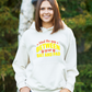 A lady wearing a white hoodie with Mind the Gap Between Your Bat and Pad on the front. A Funny Cricket Hoodie, Premium Fabric, Multiple Adult Sizes