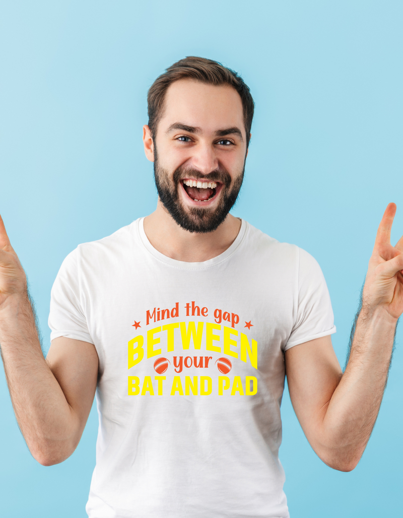 A man wearing a white t-shirt with Mind the Gap Between Your Bat and Pad on the front. A Funny Cricket Hoodie, Premium Fabric, Multiple Adult Sizes