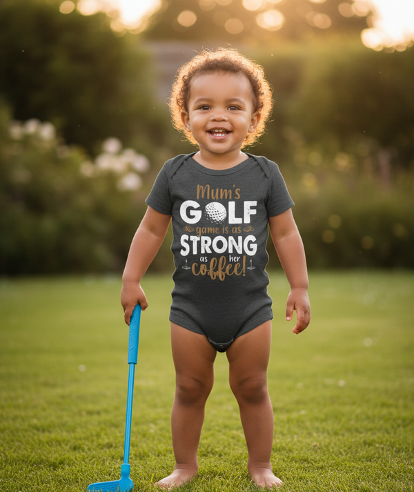 Child wearing a humorous onesie with text outdoors on grass. The baby is wearing a Cows Corner baby grow with a funny golf slogan 'Mum’s Golf Game Is As Strong as Her Coffee!'. Cows Corner gifts are perfect for sport-mad fans, these gifts work brilliantly for birthdays, new baby celebrations, Father’s Day, Mother’s Day, Christmas, anniversaries, thank you gifts, end-of-season team awards, graduations, retirements, and just-because moments when you want to raise a smile. 
