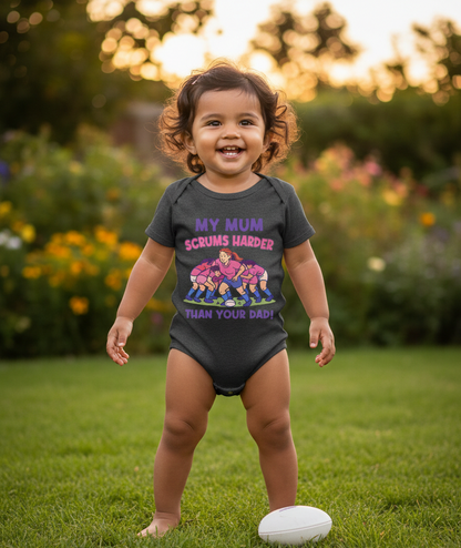 Child wearing a humorous onesie in a garden. The baby is wearing a Cows Corner baby grow with a funny rugby slogan 'My Mum Scrums Harder Than Your Dad!'. Cows Corner gifts are perfect for sport-mad fans, these gifts work brilliantly for birthdays, new baby celebrations, Father’s Day, Mother’s Day, Christmas, anniversaries, thank you gifts, end-of-season team awards, graduations, retirements, and just-because moments when you want to raise a smile. 
