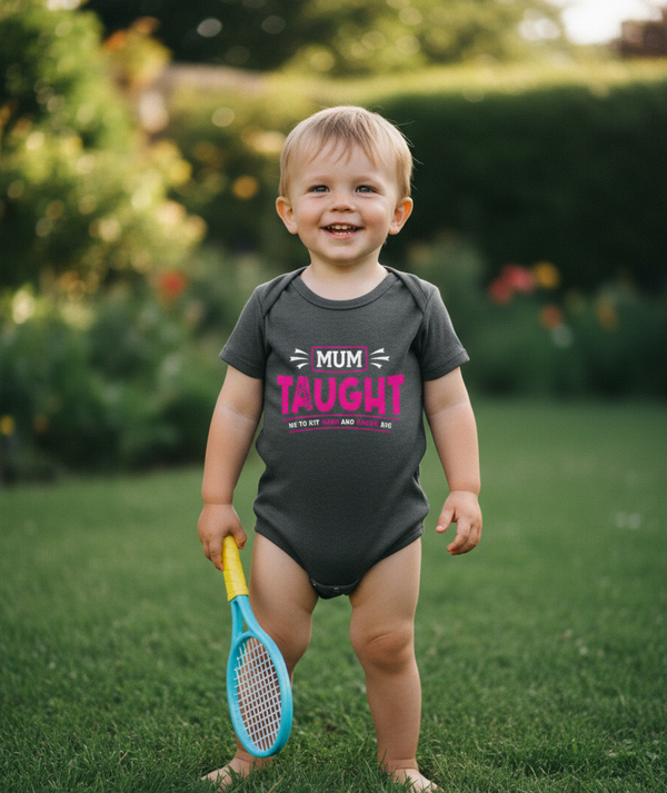 Child wearing a Cows Corner baby grow with the funny tennis slogan 'Mum Taught Me To Hit Hard and Dream Big!'. Cows Corner gifts are perfect for sport-mad fans, these gifts work brilliantly for birthdays, new baby celebrations, Father’s Day, Mother’s Day, Christmas, anniversaries, thank you gifts, end-of-season team awards, graduations, retirements, and just-because moments when you want to raise a smile. 
