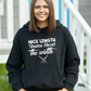 A lady wearing a black hoodie with Nice Length, Shame About The Width on the front. A Funny Cricket Hoodie, Premium Fabric, Multiple Adult Sizes