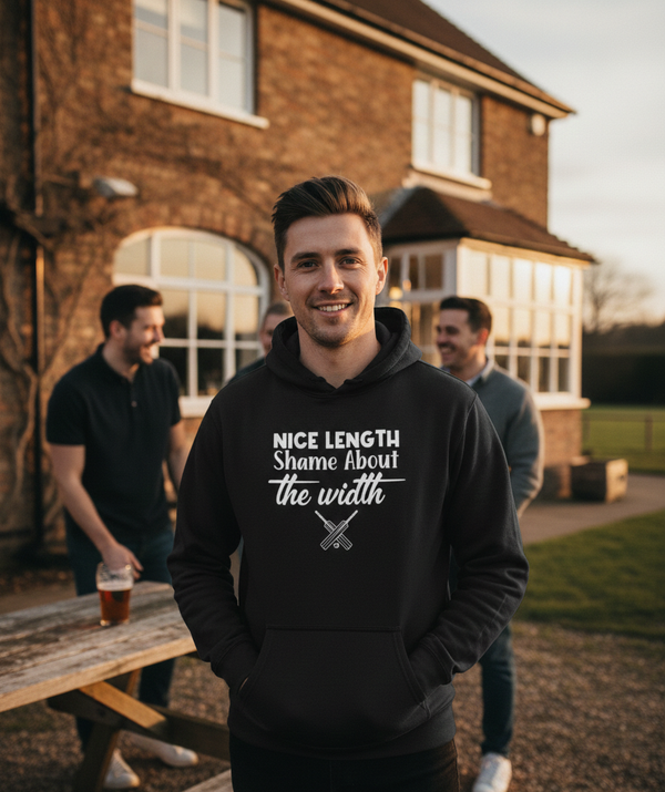 Man wearing a black hoodie with text standing outdoors near a brick building. The man is wearing a Cows Corner hoodie with a funny cricket slogan 'Nice length shame about the width'. Cows Corner gifts are perfect for sport-mad fans, these gifts work brilliantly for birthdays, new baby celebrations, Father’s Day, Mother’s Day, Christmas, anniversaries, thank you gifts, end-of-season team awards, graduations, retirements, and just-because moments when you want to raise a smile. 
