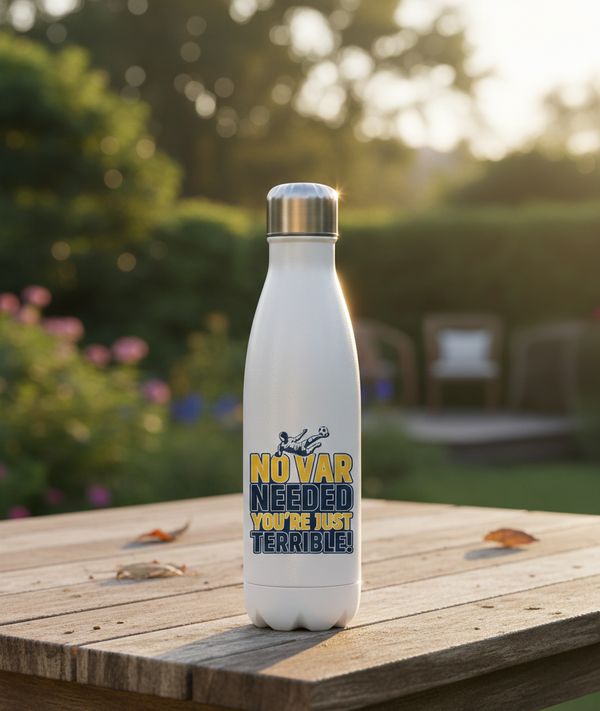 White water bottle with a humorous design on a wooden table outdoors. This is a Cows Corner water bottle with the funny football slogan 'No VAR Needed You’re Just Terrible'. Cows Corner gifts are perfect for sport-mad fans, these gifts work brilliantly for birthdays, new baby celebrations, Father’s Day, Mother’s Day, Christmas, anniversaries, thank you gifts, end-of-season team awards, graduations, retirements, and just-because moments when you want to raise a smile. 
