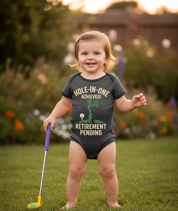 Child wearing a onesie with a humorous retirement message, standing outdoors with a golf club. The baby is wearing a Cows Corner baby grow with a funny darts slogan 'Hole-In-One Achieved… Retirement Pending'. Cows Corner gifts are perfect for sport-mad fans, these gifts work brilliantly for birthdays, new baby celebrations, Father’s Day, Mother’s Day, Christmas, anniversaries, thank you gifts, end-of-season team awards, graduations, retirements, and just-because moments when you want to raise a smile. 

