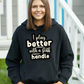 A lady wearing a black hoodie with I Play Better with a Stiff Handle, on the front. A  Funny Cricket Hoodie, Premium Fabric, Multiple Adult Sizes