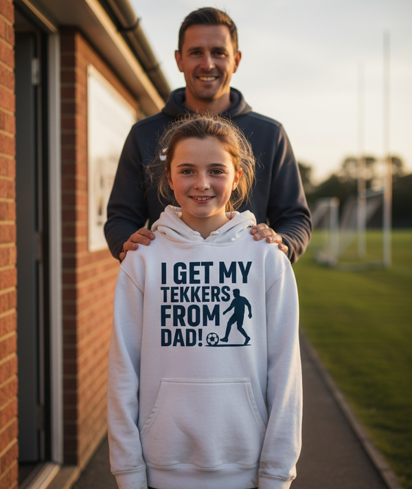 Man and child wearing a hoodie with text standing outdoors. The girl is wearing a Cows Corner hoodie with a funny football slogan 'I Get My Tekkers From Dad'. Cows Corner gifts are perfect for sport-mad fans, these gifts work brilliantly for birthdays, new baby celebrations, Father’s Day, Mother’s Day, Christmas, anniversaries, thank you gifts, end-of-season team awards, graduations, retirements, and just-because moments when you want to raise a smile. 
