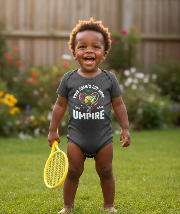 Child wearing a onesie with a sports-themed design, holding a yellow toy tennis racket in a garden setting. The baby is wearing a Cows Corner baby grow with a funny tennis slogan 'Your Game's Got More Faults Than A Bad Umpire'. Cows Corner gifts are perfect for sport-mad fans, these gifts work brilliantly for birthdays, new baby celebrations, Father’s Day, Mother’s Day, Christmas, anniversaries, thank you gifts, end-of-season team awards, graduations, retirements, and just-because moments 