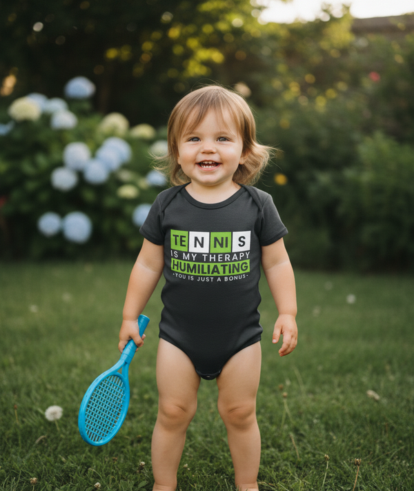 Child wearing a humorous tennis-themed onesie outdoors.  The baby is wearing a Cows Corner baby grow with a funny tennis slogan 'Tennis Is My Therapy, Humiliating You Is Just A Bonus'. Cows Corner gifts are perfect for sport-mad fans, these gifts work brilliantly for birthdays, new baby celebrations, Father’s Day, Mother’s Day, Christmas, anniversaries, thank you gifts, end-of-season team awards, graduations, retirements, and just-because moments when you want to raise a smile. 
