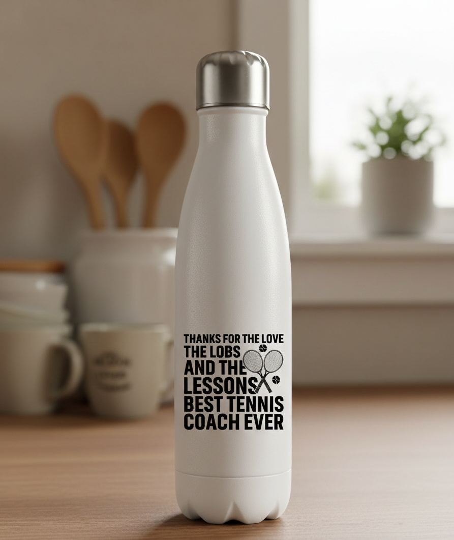 White insulated bottle with text on a kitchen counter. This is a Cows Corner water bottle with a funny tennis slogan 'Thanks for the Love the Lobs and the Lessons. Best Tennis Coach Ever'. Cows Corner gifts are perfect for sport-mad fans, these gifts work brilliantly for birthdays, new baby celebrations, Father’s Day, Mother’s Day, Christmas, anniversaries, thank you gifts, end-of-season team awards, graduations, retirements, and just-because moments when you want to raise a smile. 

